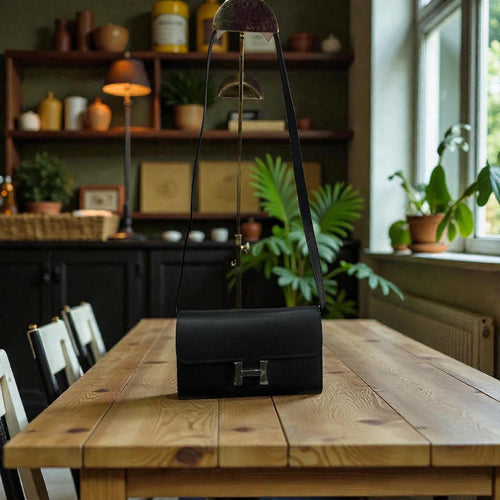 Bandoulière  Hermès noire avec un portefeuille a l'intérieur